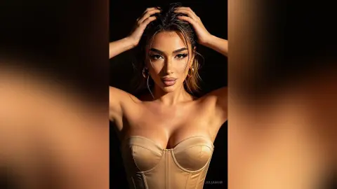 Glamorous woman in a beige corset top posing with dramatic lighting in a moody studio setting.