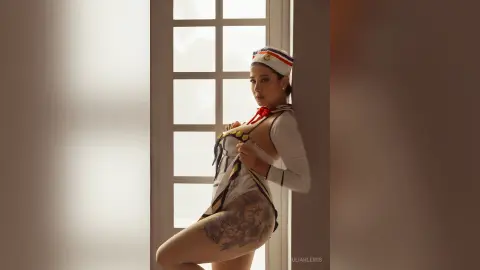 JuliahLewis poses in a white and gold waitress outfit, pulling down her top to reveal her breasts while standing by a window.