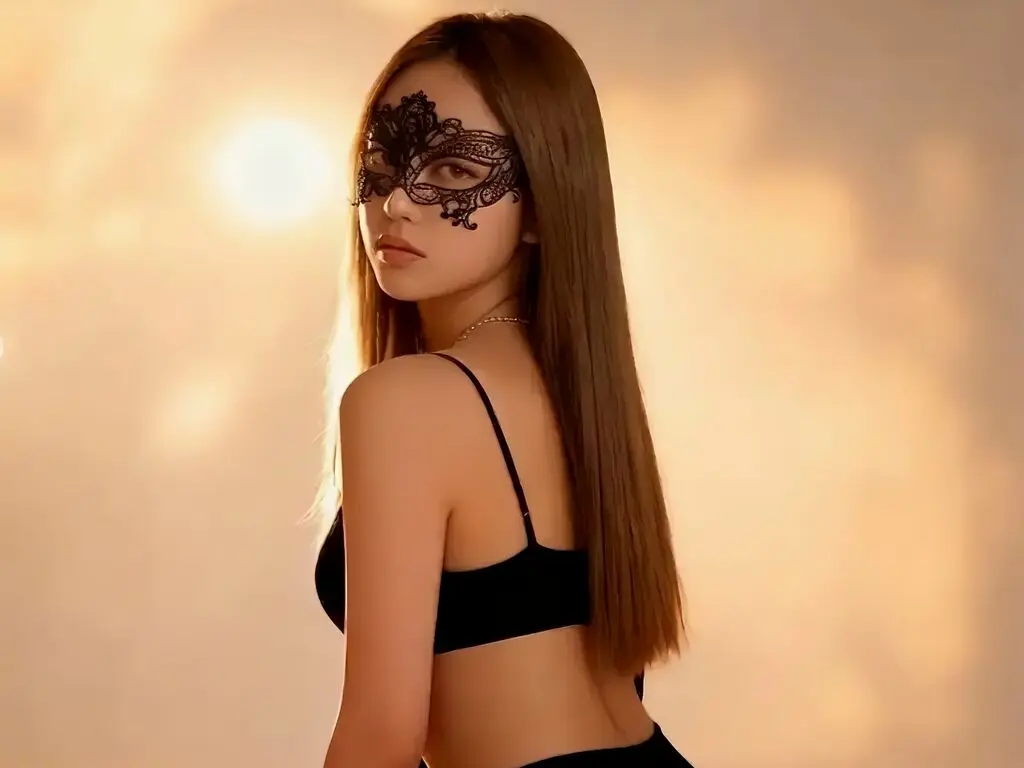 Mysterious woman in a black lace masquerade mask and black camisole posing against a warm, glowing background.