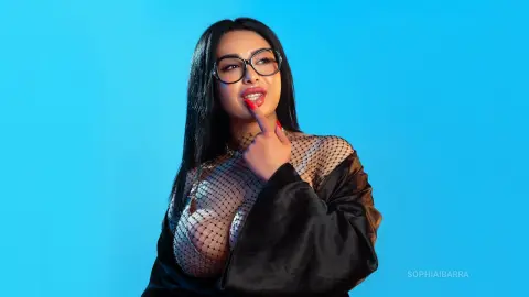 Curvy woman with long dark hair and glasses wearing a black mesh top against a bright blue studio background.