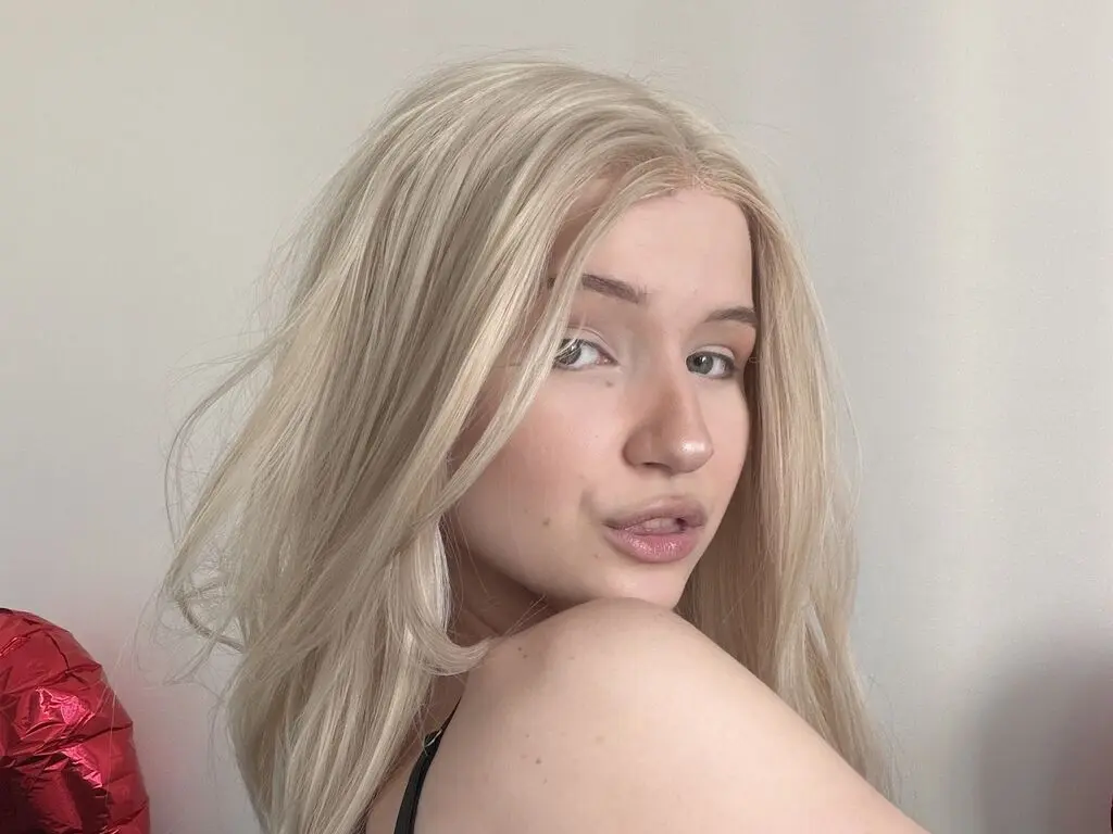 Blonde woman in a black top posing with a soft, natural look against a plain white background.