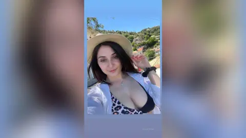 Smiling woman in a straw hat and leopard print bikini enjoying a sunny summer day outdoors.