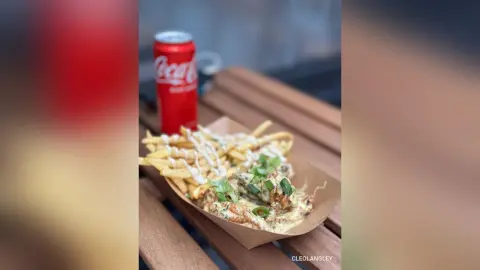 Crispy loaded chicken fries with creamy sauce and a red soda can on a wooden outdoor table.