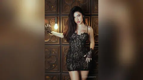 Elegant woman in a black lace cocktail dress and gloves posing against a vintage carved wood wall.