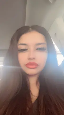 Young woman with long dark hair and soft makeup posing for a dreamy, sun-drenched selfie.