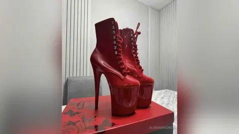 AlienaMoore — AlienaMoore's red patent leather platform high heel boots sit on a red box in a white room.