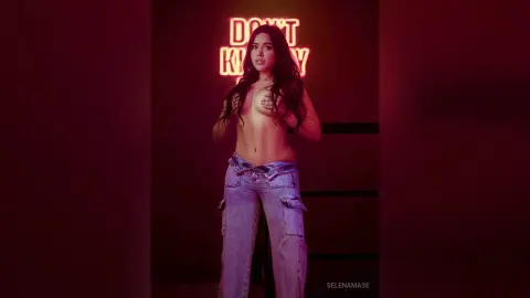 Young woman in denim cargo pants posing under red neon lights in a moody, cinematic setting.
