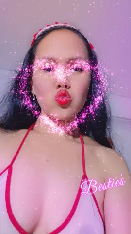 Young woman in a red bikini top making a kissy face with a sparkling pink heart filter effect.