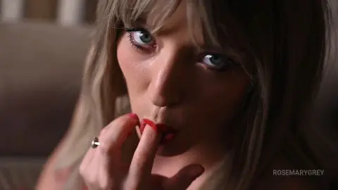RosemaryGrey looks into the camera with a seductive gaze while licking her lips and biting her finger.