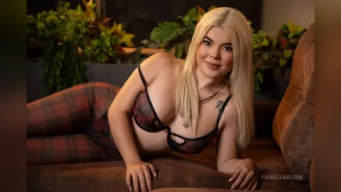 FiorellaRossi lies on a brown sofa wearing a black and red plaid bra and matching plaid leggings.