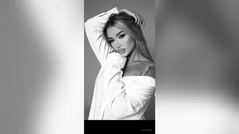 Glamorous woman in a white oversized shirt posing with a moody, high-fashion aesthetic in black and white.