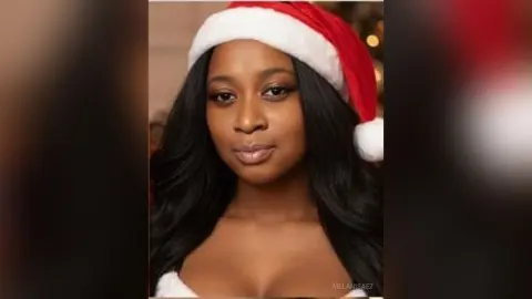 Beautiful Black woman wearing a festive red and white Santa hat with a soft, joyful holiday mood.