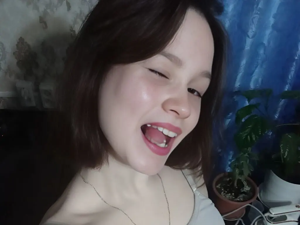 Cheerful young woman with short brown hair laughing in a cozy indoor setting.
