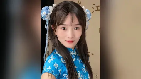 Young woman in a blue floral traditional Chinese cheongsam with elegant white flower hair accessories.