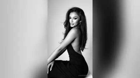 Elegant woman in a black backless dress posing for a moody black and white studio portrait.