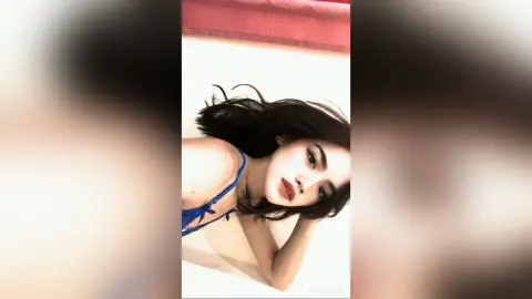 NancyLoppez poses with her dark hair loose, wearing a blue string bikini top against a white background.