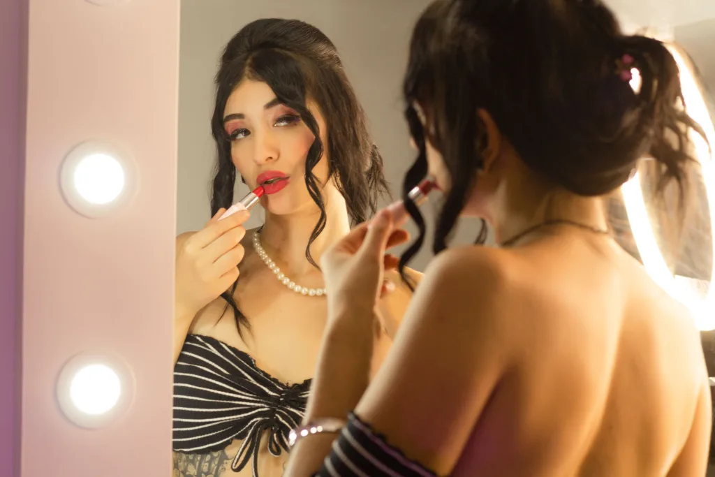 TiffanySantana poses naked in a dark bathroom, showing her bare breasts, pussy, and tattoos while looking at the camera.