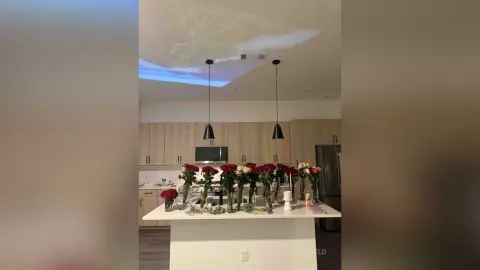 Elegant bouquet of red roses on a white kitchen island in a modern, dimly lit home interior.