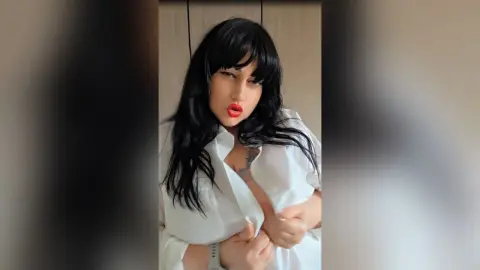 Beautiful woman with long black hair in an unbuttoned white shirt posing with a confident mood indoors.