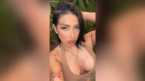 KimRoberth poses with wet-look dark hair, wearing a tan tank top and a gold necklace.