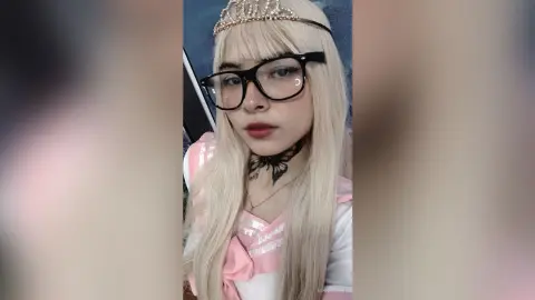 Blonde girl in pink princess cosplay wearing a gold tiara and black glasses with a soft aesthetic mood.