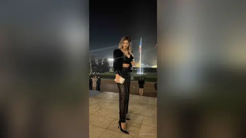 Stylish woman in a black velvet crop top and sequin pants posing at an elegant outdoor night event.