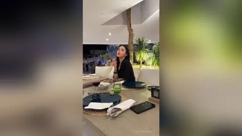 Elegant woman in a black top dining at a luxury outdoor restaurant at night.