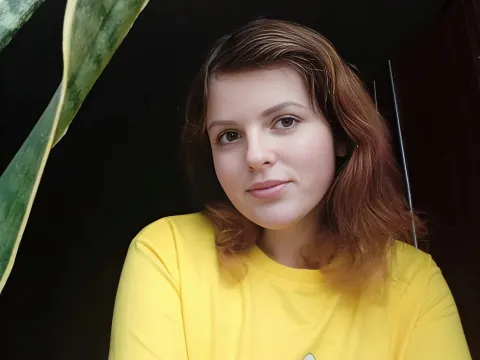 Stacey L — Stacey L wears a yellow t-shirt and looks toward the camera with her reddish-brown hair framing her face.