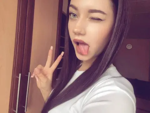 Sonny Chuck — Sonny Chuck winks and sticks her tongue out while making a peace sign in a white t-shirt.