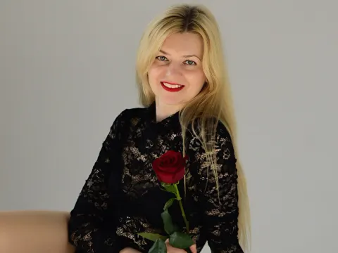 Melissa Tyler — Melissa Tyler smiles while holding a single red rose, wearing a black lace long-sleeve top.