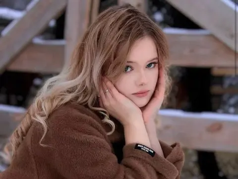 Parthenia Prudden — Parthenia Prudden poses outdoors in a brown fuzzy sweater with her hands resting on her cheeks.