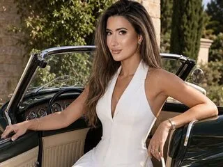 Adeline Rosse wears a white halter jumpsuit while sitting in the driver's seat of a vintage convertible car.