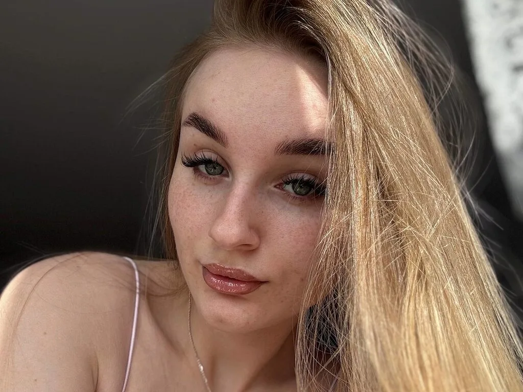 Alice Stacy looks directly at the camera with long blonde hair and light freckles on her face.