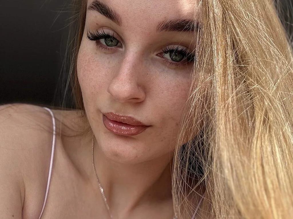 Alice Stacy looks directly at the camera with long blonde hair and light freckles on her face.