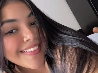 Sally Rosie smiles while lying down with her long black hair spread out around her shoulders.