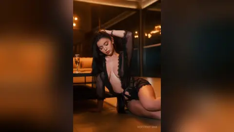 Elegant woman in black lace lingerie relaxing in a moody, dimly lit luxury lounge setting.
