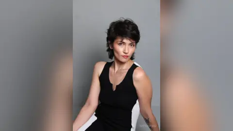 IveteDurand poses in a black sleeveless top with short dark hair against a plain grey background.