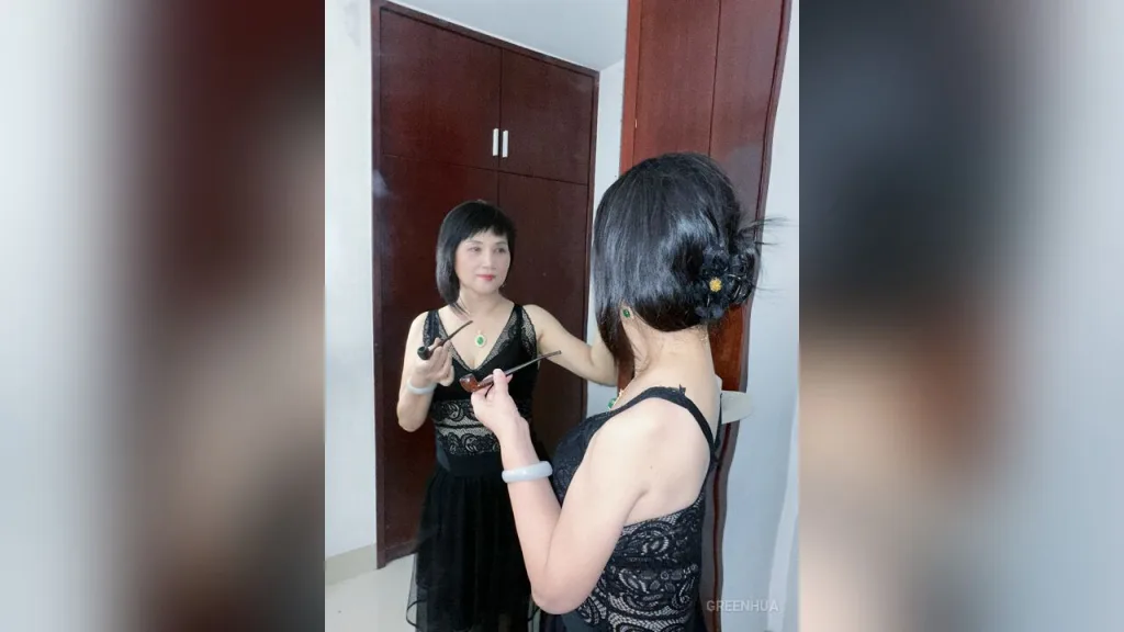 GreenHua — GreenHua stands in front of a dark wood wardrobe wearing a black lace dress and holding sunglasses.