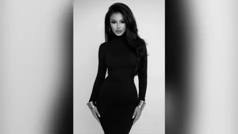Elegant woman in a sleek black turtleneck dress posing against a minimalist studio background in black and white.