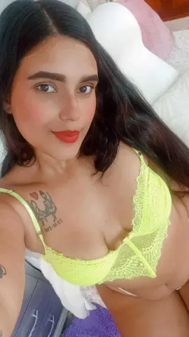 Smiling young woman in a bright yellow lace bralette relaxing in a cozy bedroom setting.