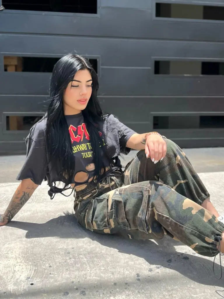 MilaMonty shows off her long dark hair and heavy tattoos while looking directly at the camera with a pouty expression.
