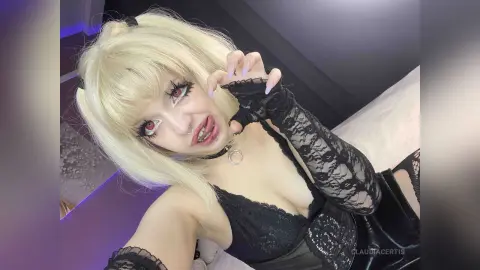 Gothic girl with blonde pigtails and red eyes wearing a black lace outfit in a moody bedroom setting.