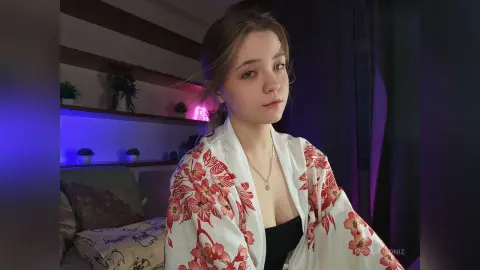 Young woman in a white floral kimono robe relaxing in a room with moody purple ambient lighting.