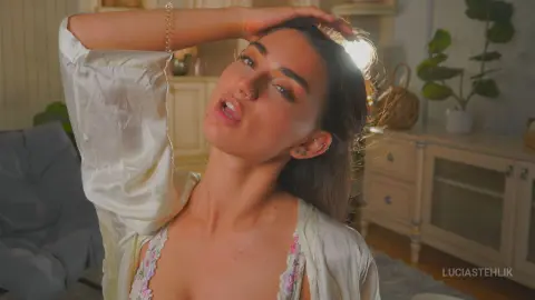 Young woman in a white silk robe relaxing in a sunlit bedroom with a peaceful mood.