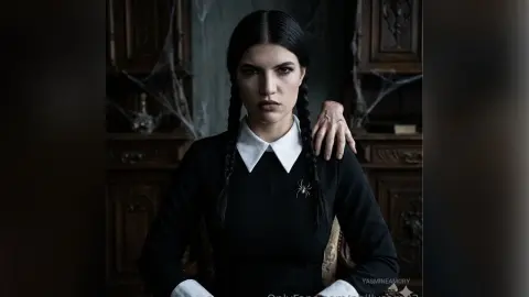 Moody portrait of a woman with dark braids in a black dress and white collar in a gothic vintage room.