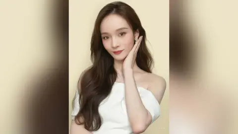 Elegant woman in a white off-the-shoulder top posing with a serene expression against a neutral background.