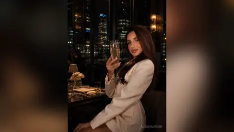 Elegant woman in a white blazer holding a champagne glass at a luxury rooftop bar overlooking a city skyline.