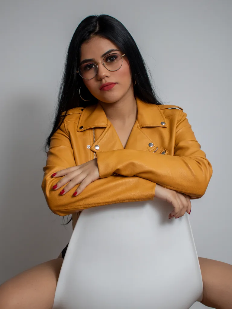 GabyRiveraa poses in a black long-sleeve crop top that shows her chest and cleavage, looking at the camera with long dark hair.
