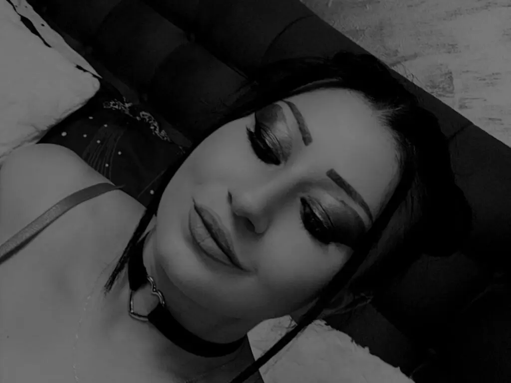 Moody black and white portrait of a woman with dramatic eye makeup wearing a black choker choker necklace.
