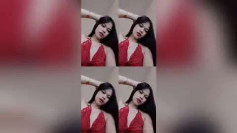 Young woman in a stylish red sleeveless top posing confidently against a neutral indoor background.